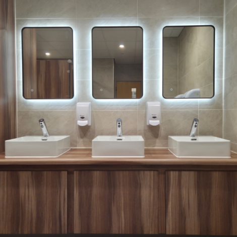 Back lit mirrors on vanity unit for commercial washroom