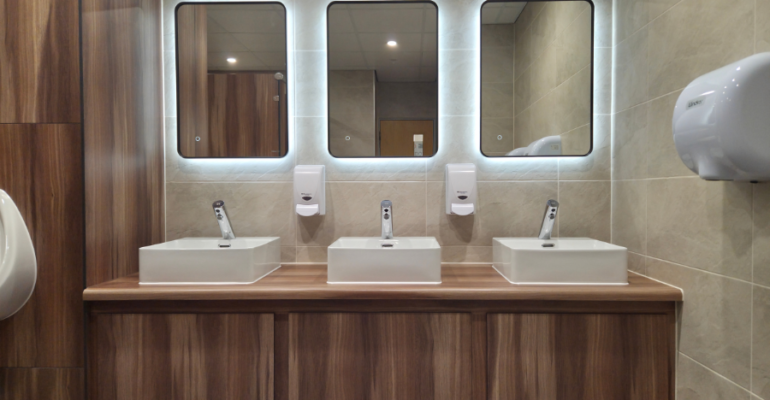Back lit mirrors on vanity unit for commercial washroom